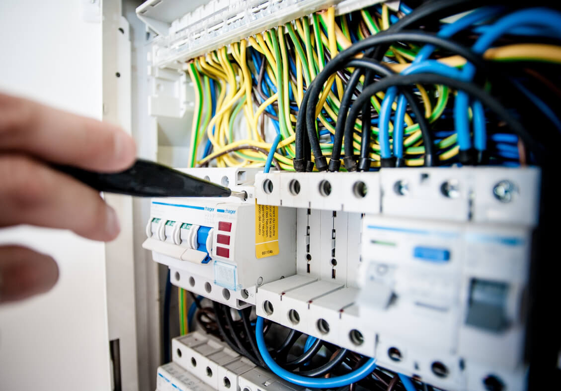 A Facilities Management professional removes wires from an electrical panel.