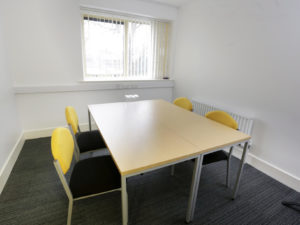 A room furnished with a table and chairs, offering a view through a window, at The Business Hive.