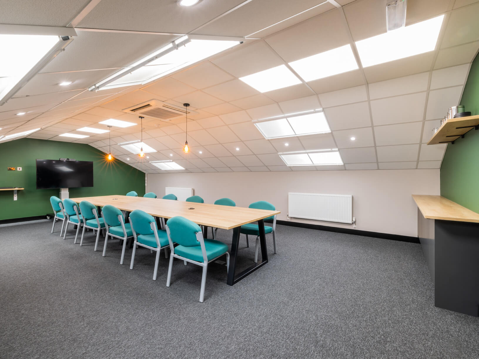 A conference room in The Enterprise Village with a green table and chairs.