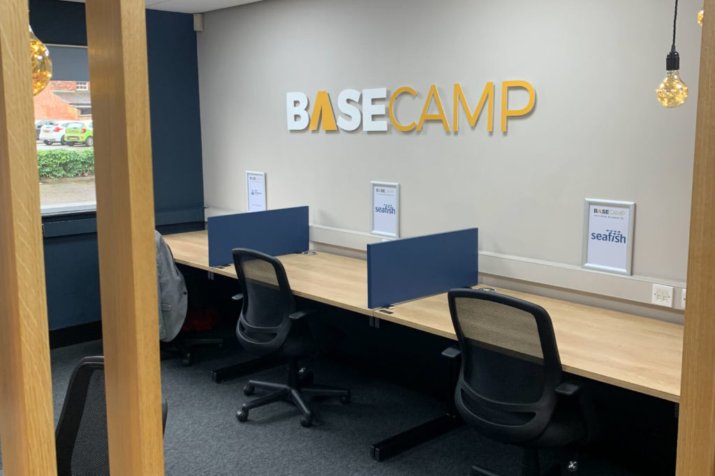 An office space featuring desks and a prominent BaseCamp sign.