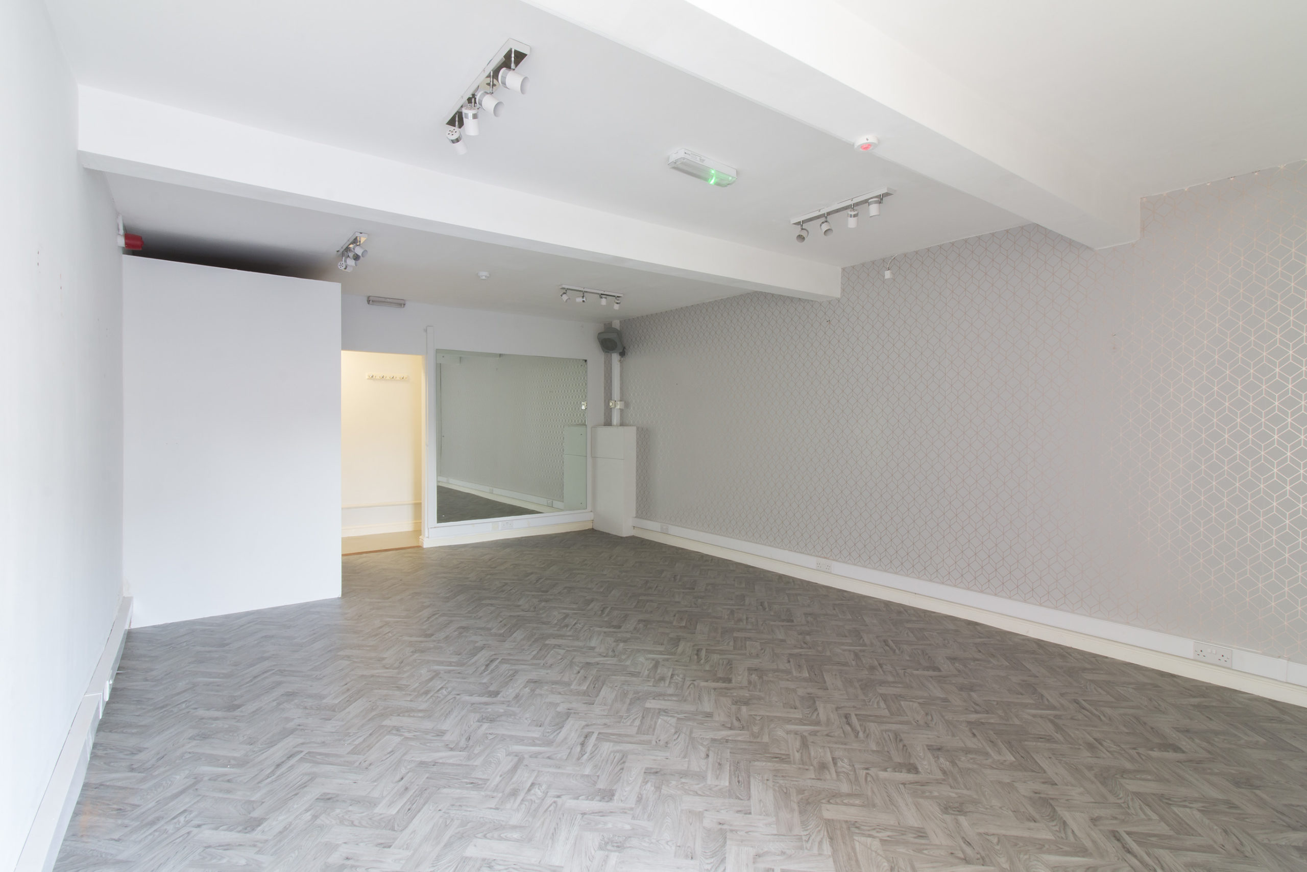 An empty retail unit with grey walls and wooden floors located in Grimsby at 170 Yarbrough Road.