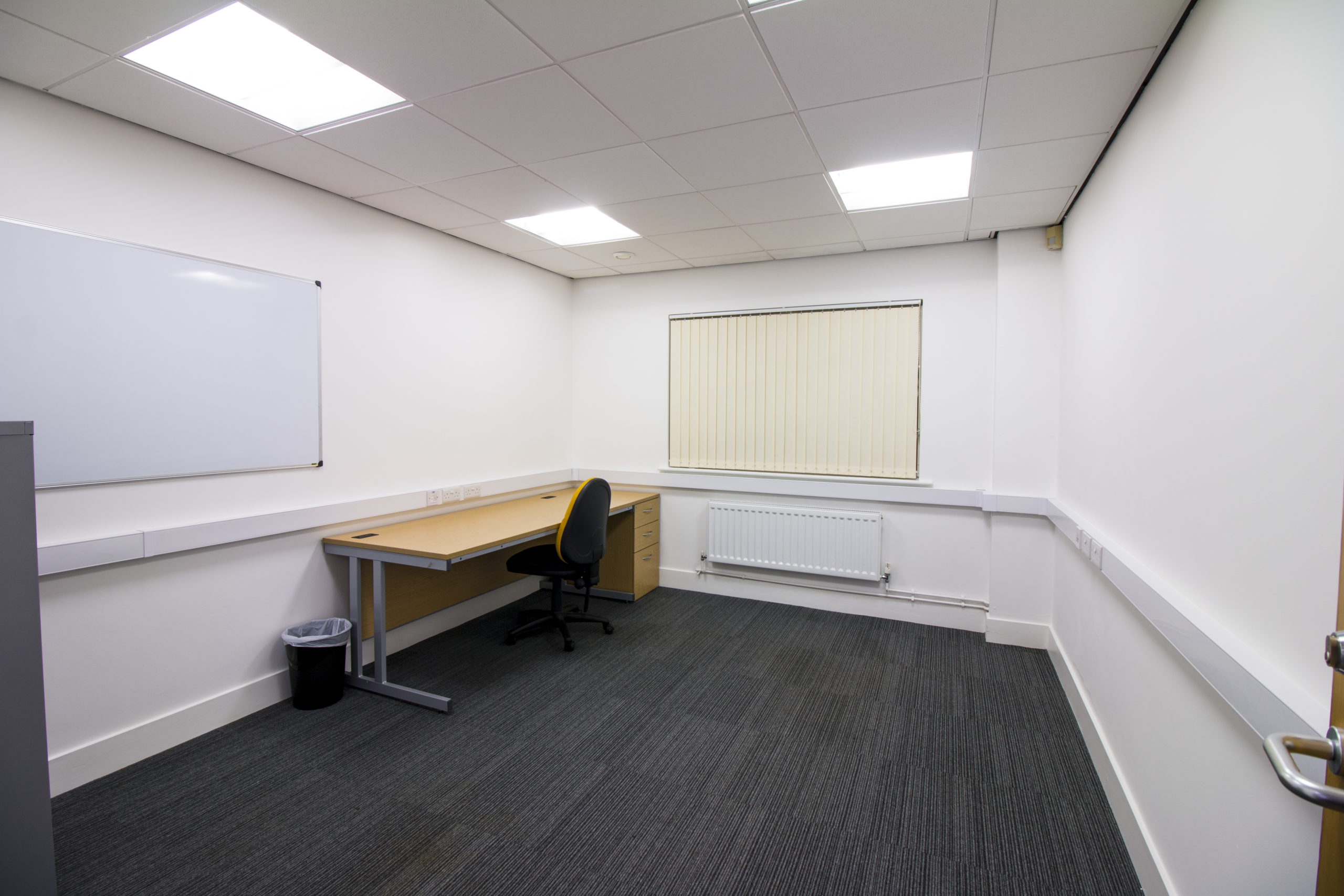 An empty office at 13 Dudley Street in Grimsby, equipped with a desk and a whiteboard.