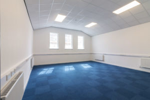 An empty office with blue carpet and white walls.