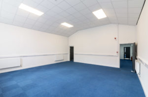 An empty office with blue carpet and white walls at 84 Wellington Street in Grimsby.