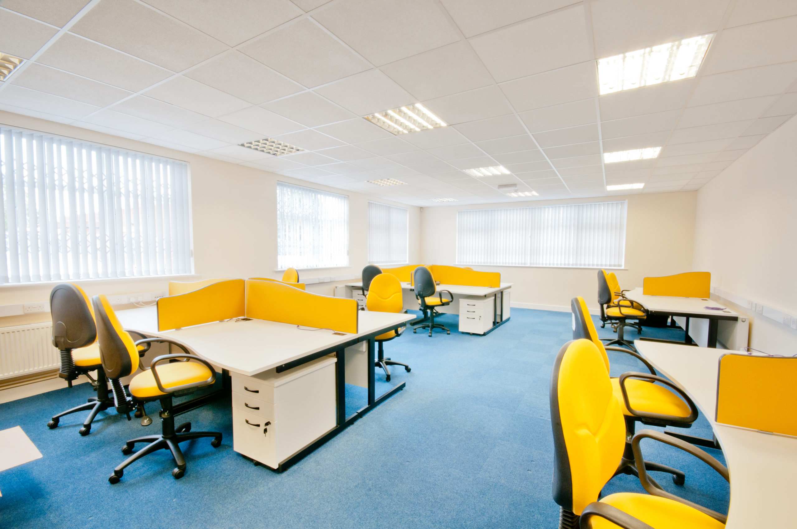 An empty office at Lunar House with yellow desks and chairs.